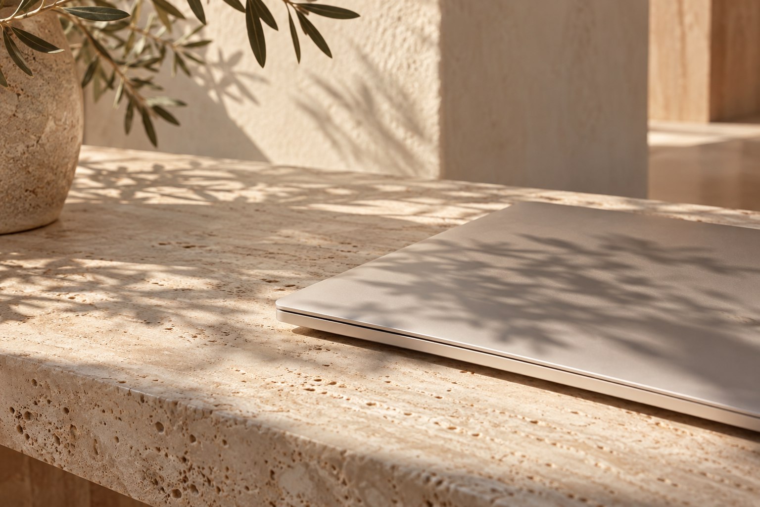 Notebook sobre bancada de travertino com sombras naturais
